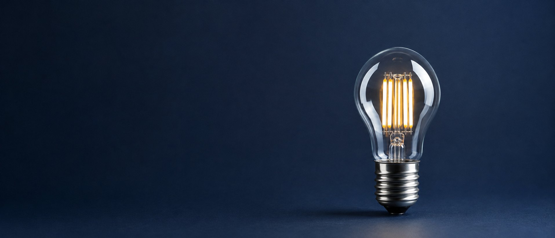 LED filament bulb on a deep navy background